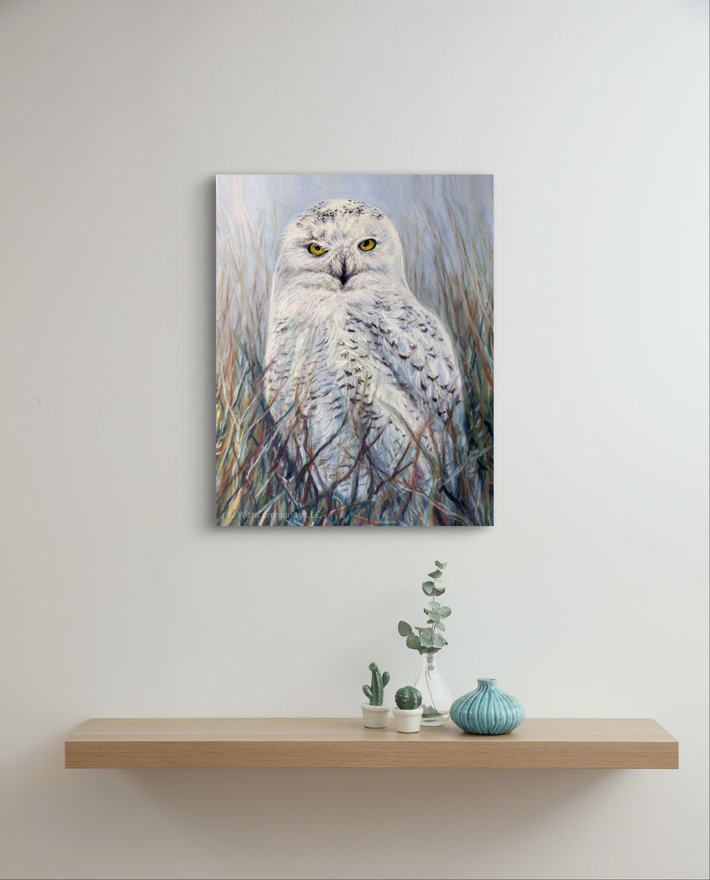 Canvas print of an owl in a natural setting on a wall above a wooden shelf with decorative items.