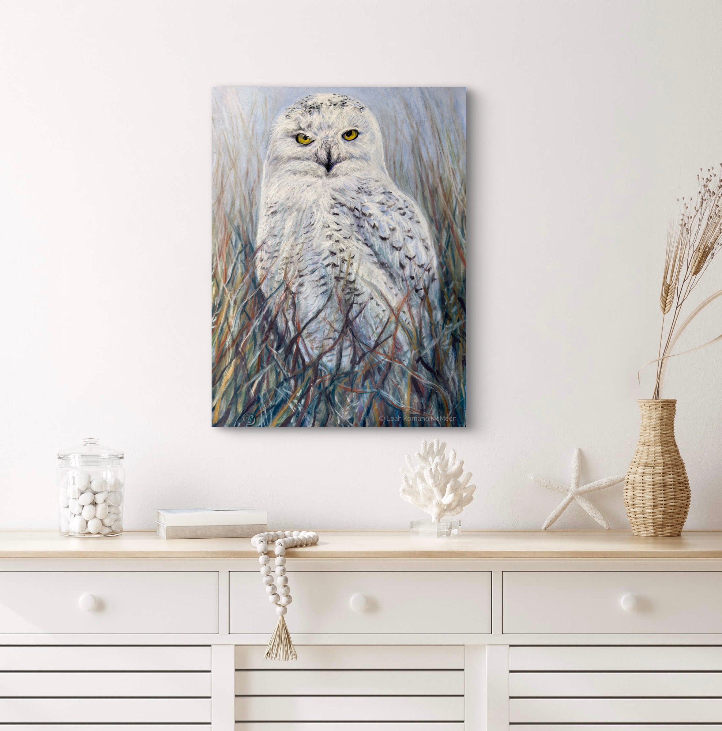 Canvas print of a snowy owl in natural setting on a wall above a white console table.