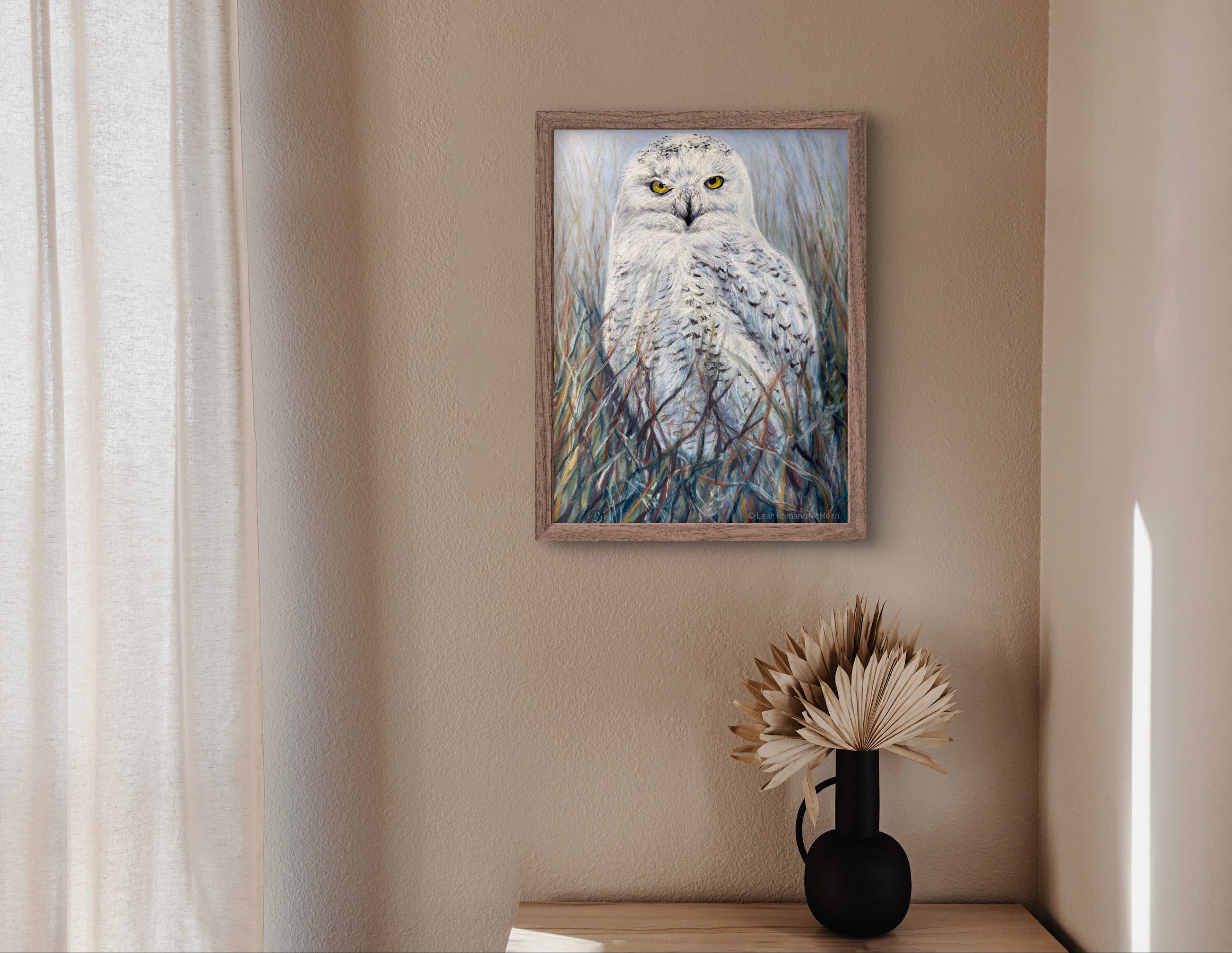 Framed painting of an owl on a wall above a shelf with a vase and dried plants.