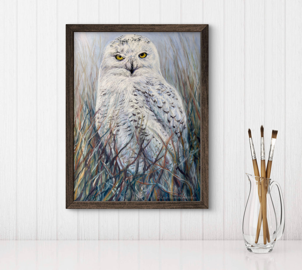 Framed artwork of an owl in a natural setting on a white wall.