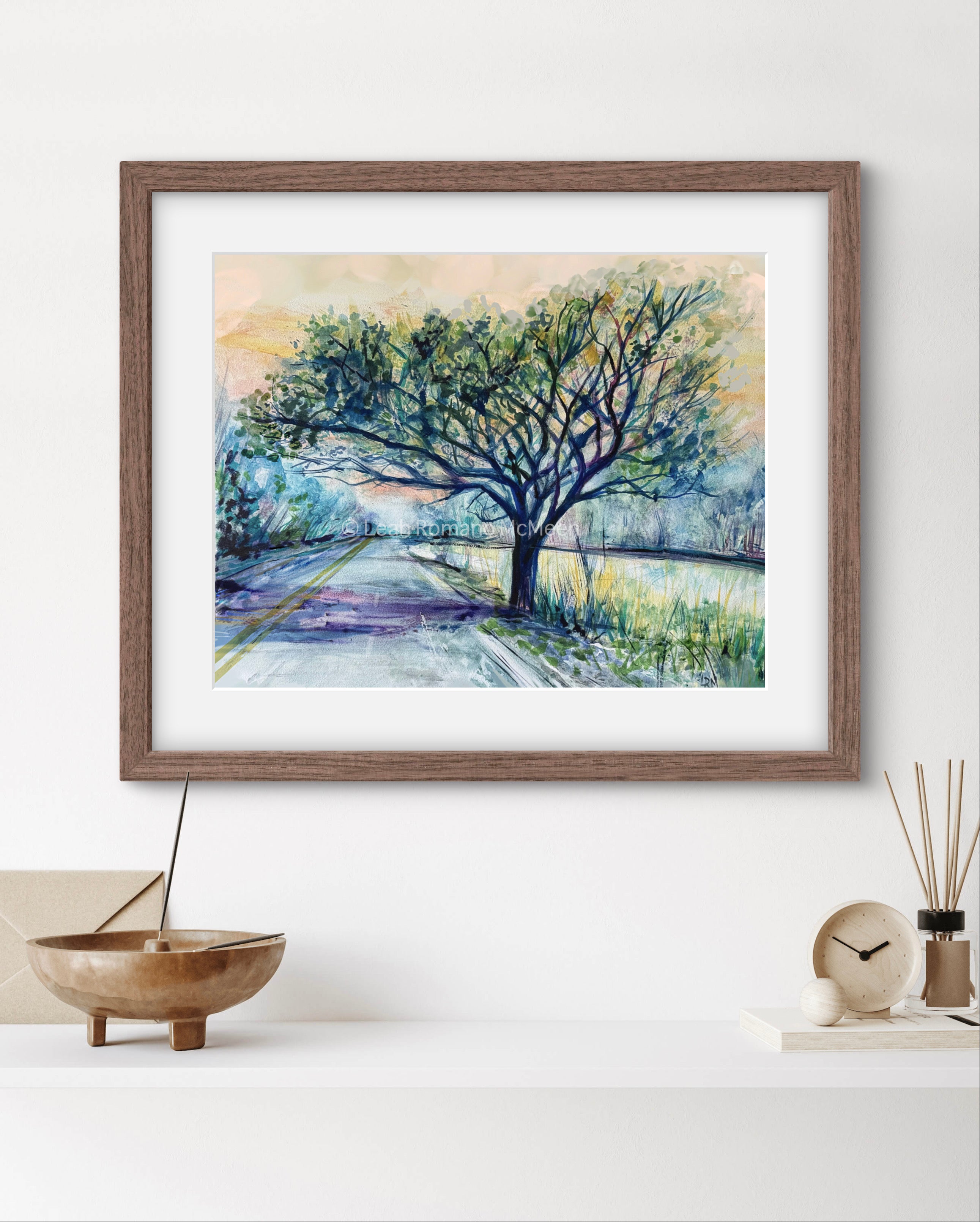 Framed painting of a tree on a white wall.